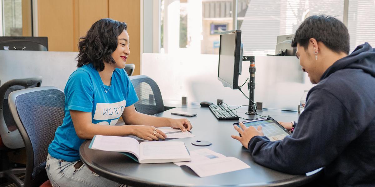 Students talking to one another at a desk.